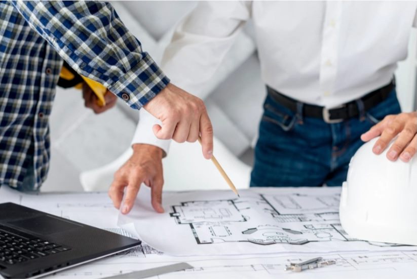 Equipo de trabajo señalando un plano sobre la mesa