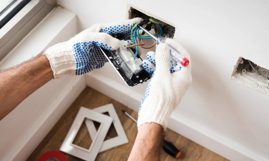 Electricista instalando una caja eléctrica en un muro