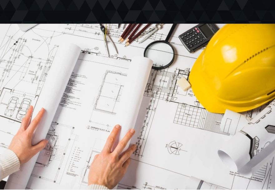 Planos, casco y herramientas de dibujo sobre una mesa de trabajo